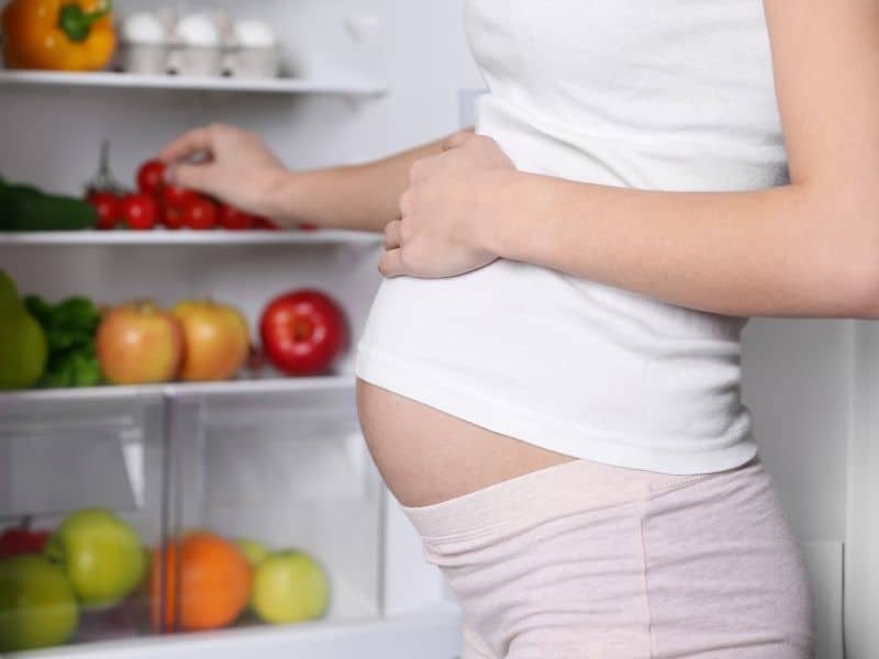 pregnant woman looking in a fridge